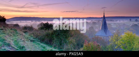 Early morning autumnal mist over East Meon village with Butser Hill and the South Downs in the background, South Downs National Park, Hampshire, UK Stock Photo