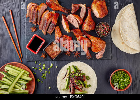 close-up of Juicy Peking Duck Carved Table-Side with extremely crispy flavour skin on a black slate served with mandarin pancakes,cucumber sticks and  Stock Photo