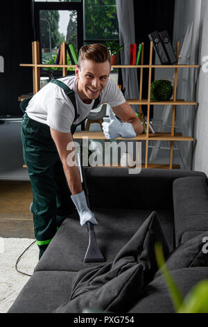 Male Worker Cleaning Sofa With Vacuum Cleaner Stock Photo