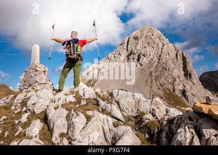 Hiker cheering elated and blissful with arms raised in the sky after hiking to mountain top summit above the clouds.  Success concept Stock Photo