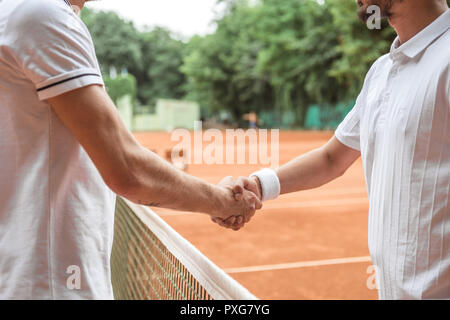 cropped view of tennis players shaking hands after game on court Stock Photo