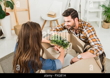 partial view of young couple unpacking cardboard boxes together at new home, moving home concept Stock Photo