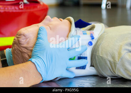 Human hands stabilisations the neck from a medical training puppet for ambulance man Stock Photo