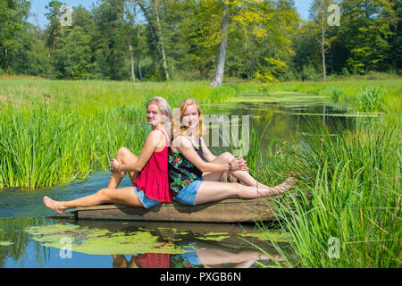 Two young caucasian women sitting at stream in nature Stock Photo