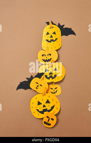 Different handcraft scary pumpkins and bats on a brown background with space for text. Creative composition for Halloween. Flat lay Stock Photo