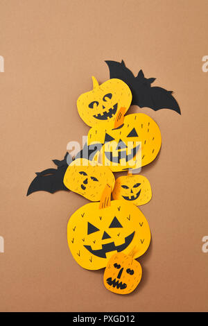 Smiling scary pumpkins and bat handcraft of paper on a brown background with space for text. Halloween. Flat lay Stock Photo