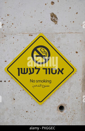 Yellow, NO SMOKING sign in Hebrew and Arabic on a concrete wall Stock Photo