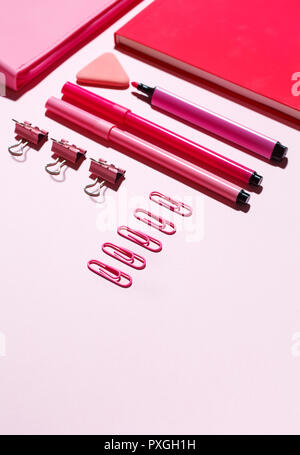 Pink paper clips, pink notebook and pink pencil case on a pink background. Stock Photo