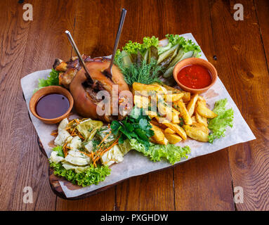 moked pork leg with potatoes, pickled cucumbers, cabbage, parsley, salad, dill and red sauce. Stock Photo