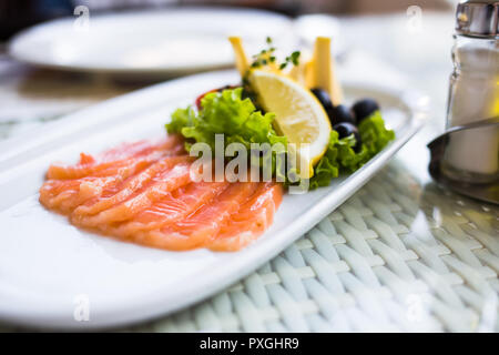 sliced smoked salmon served with lemon slices on white plate. Stock Photo