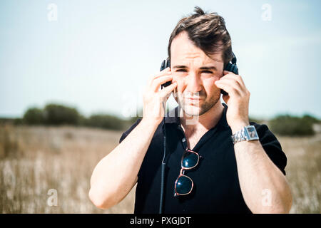 Young attractive man wearing black enjoying music on his headphones Stock Photo