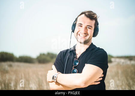 Young attractive man wearing black enjoying music on his headphones Stock Photo
