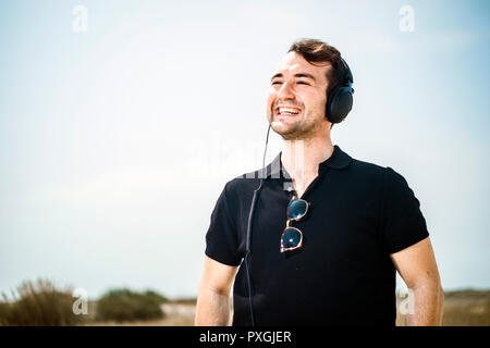 Young attractive man wearing black enjoying music on his headphones Stock Photo