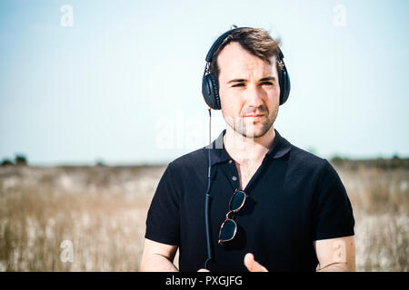 Young attractive man wearing black enjoying music on his headphones Stock Photo