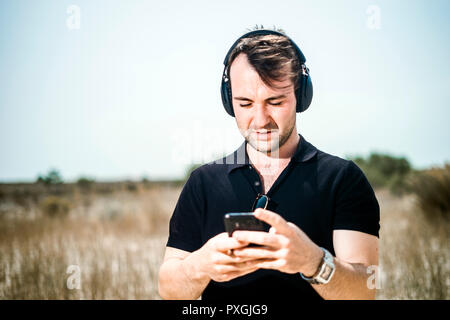 Fashionable young man playing music from his smartphone on his headphones Stock Photo