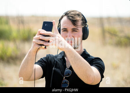 Fashionable young man playing music from his smartphone on his headphones Stock Photo