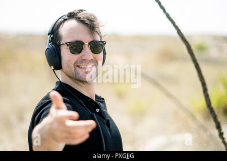 Young attractive man wearing sunglasses enjoying music on his headphones Stock Photo