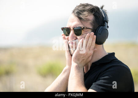 Troubled, young, attractive man wearing sunglasses and headphones Stock Photo