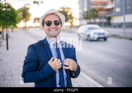 Lifestyle portrait of vintage looking young man in suit with sunglasses at sunset Stock Photo