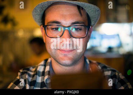 Young man using internet on his telephone in the restaurant at the evening Stock Photo