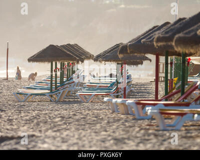 Colorful sun beds under straw umbrellas on the beach of Algarve, Portugal Stock Photo