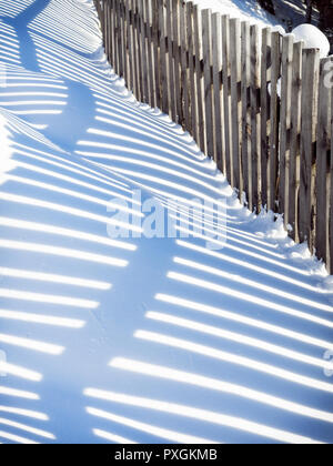 Wavy shadow from a wooden fence on snowdrifts Stock Photo