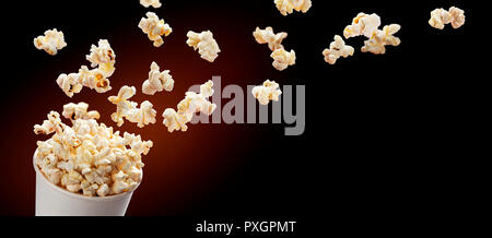Popcorn flying out of cardboard box. Isolated on black background Stock Photo