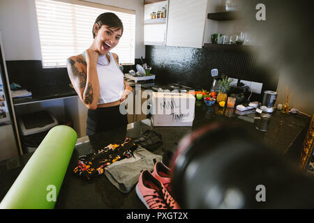 Excited woman holding a sports bra looking at camera and laughing. She is recording content for her vlog on female sportswear. Female recording new sp Stock Photo