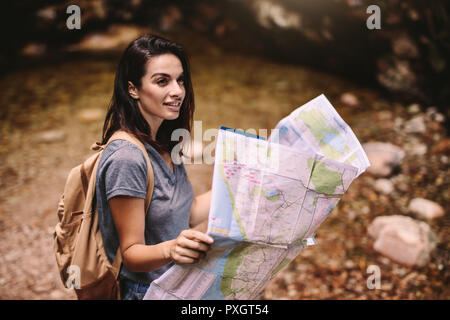 Beautiful woman hiker in mountain with map. Woman hiking with navigation map looking away and smiling. Stock Photo
