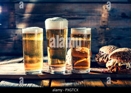 Street food. A two big burgers with glasses of light beer. On a wooden background. close up. rustic style Stock Photo