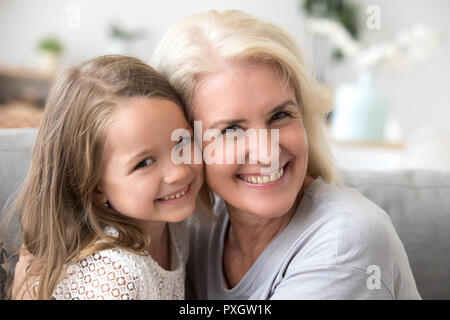 Portrait of smiling grandmother and granddaughter hugging at hom Stock Photo