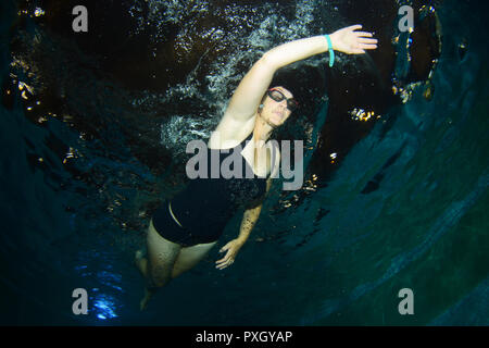 Underwater photo of a female swimmer training in the evening Stock Photo