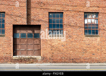 Horizontal shot of an old red brick warehouse with door and windows. Stock Photo