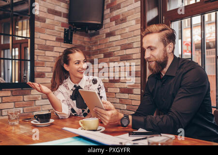 Business people are using digital tablet, drinking coffee and smiling while working in cafe Stock Photo