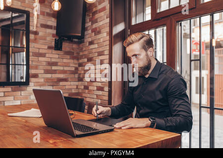 Male graphic designer working with laptop. Creative man using digital tablet and stylus pen at modern office. business, technology, design and people  Stock Photo