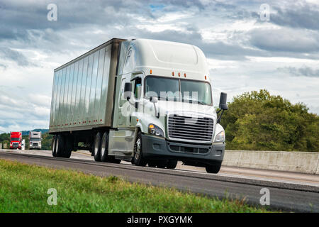 Horizontal shot of a white Tractor Trailer Rig On The Interstate under cloudy skies. Stock Photo