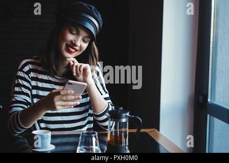 Portrait of young beautiful woman using her mobile phone in cafe.