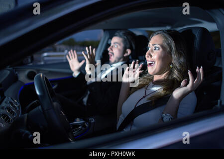 Business couple in car almost having an accident with headlight shining Stock Photo