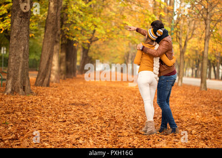 Happy couple walking in a park looking at something and pointing Stock Photo