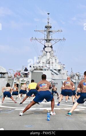 181014-N-N0146-1018 ARABIAN SEA (Oct. 14, 2018) Sailor 360 participants partake in a stretch on the flight deck before starting circuit training aboard the guided-missile destroyer USS Decatur (DDG 73). Decatur is deployed to the U.S. 5th Fleet area of operations in support of naval operations to ensure maritime stability and security in the Central Region, connecting the Mediterranean and the Pacific through the western Indian Ocean and three strategic choke points. (U.S. Navy photo by Ensign Xuan Nguyen /Released) Stock Photo
