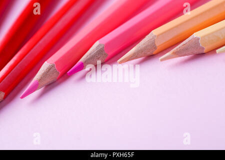 Color pencils lying on pastel pink background. Stock Photo