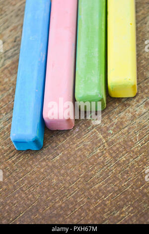 Colored chalk sticks on old wood board as copy space background. Education or back to school concept Stock Photo