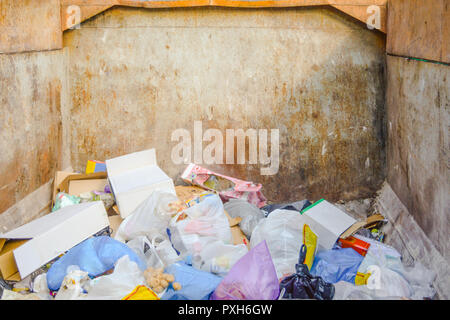 Garbage container with rubbish inside. Garbage from food waste, cans, plastic bottles and plastic bags in large rusty metal dumpster as illustration o Stock Photo