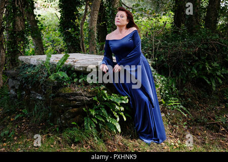 Woman wearing a blue dress photographed in a gothic cemetery - John Gollop Stock Photo