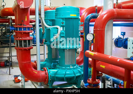 Two vertical engine painted blue with pumps connected to pipes painted red. Stock Photo