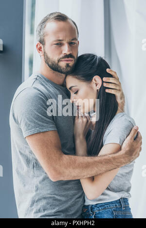 upset bearded man hugging and supporting depressed young woman Stock Photo