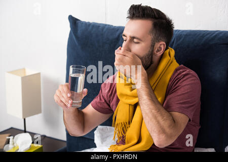 sick young man taking pills while sitting in bed Stock Photo