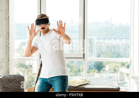 scared young man in vr headset at home Stock Photo