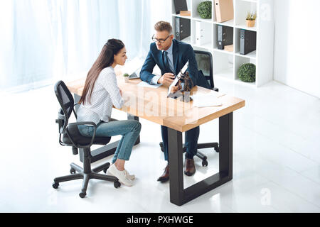 high angle view of lawyer pointing at clipboard and working with young woman in office Stock Photo