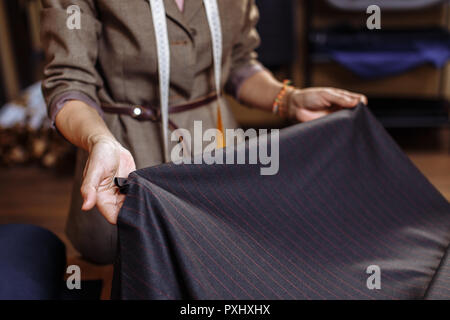 Female tailor choosing fabric for pattern cutting. Men's Wear industry, tailoring process Concept Stock Photo
